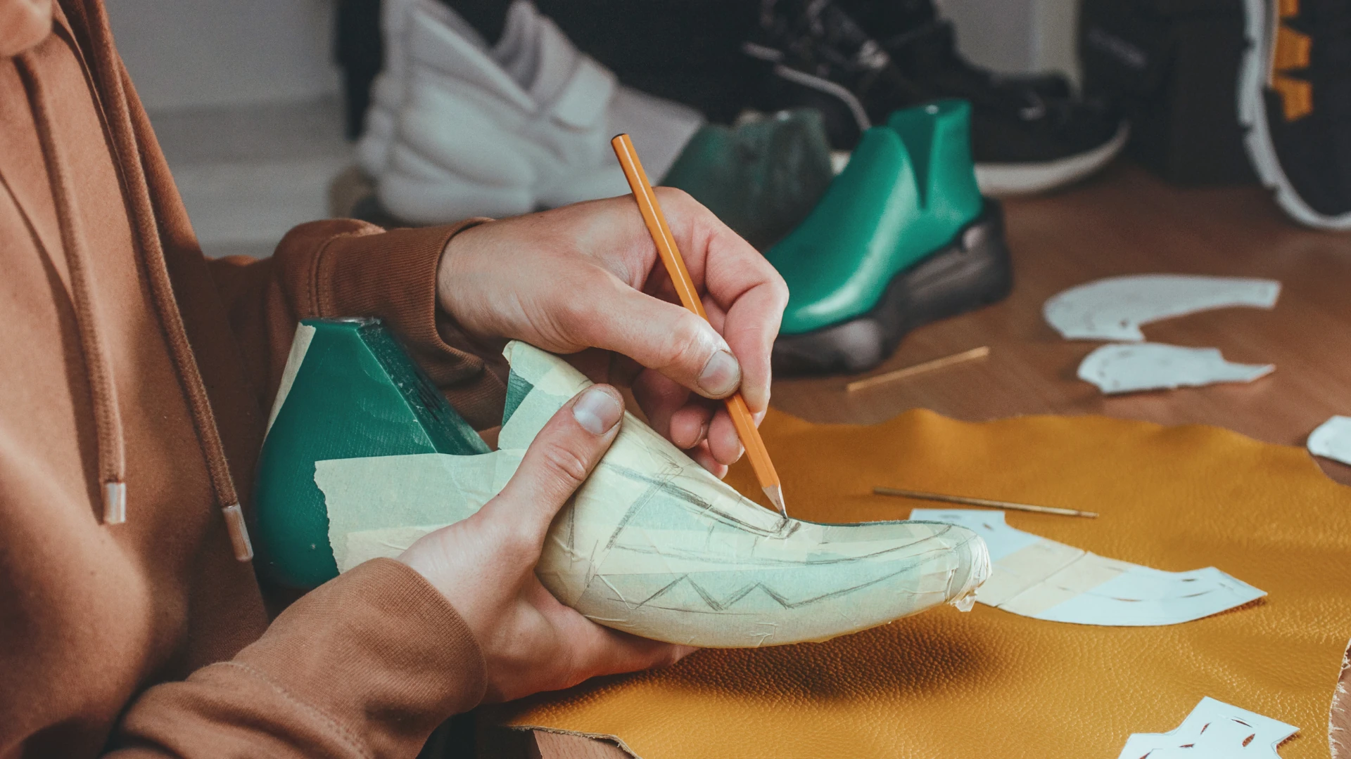 Designer hands sketching shoe prototype on last at Jerryshoes custom footwear studio